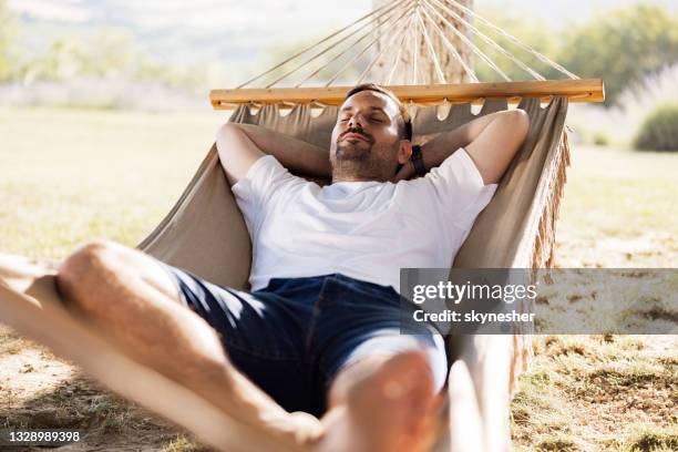 mid adult man sleeping in hammock at the backyard. - backyard hammock stock pictures, royalty-free photos & images