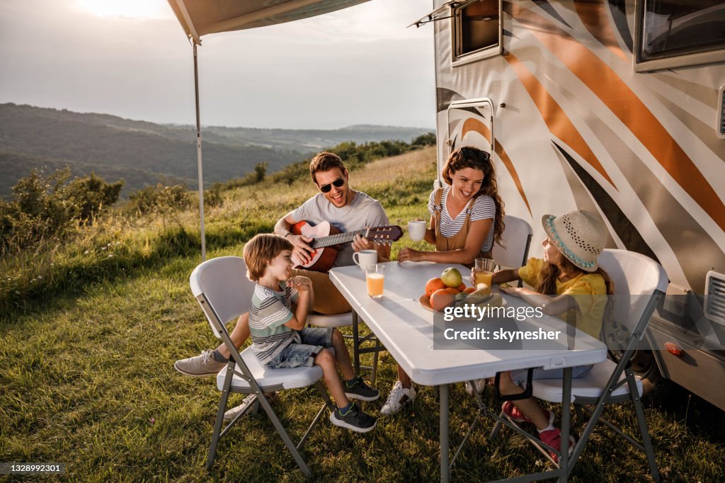 Happy family signing during their camping day by the trailer.