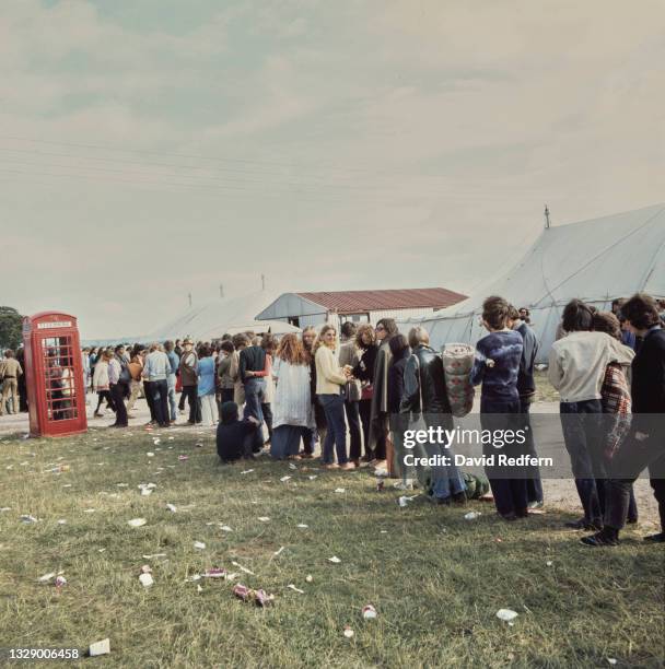 People queuing to use a red telephone box at Bath Festival Of Blues, UK, June 1970.