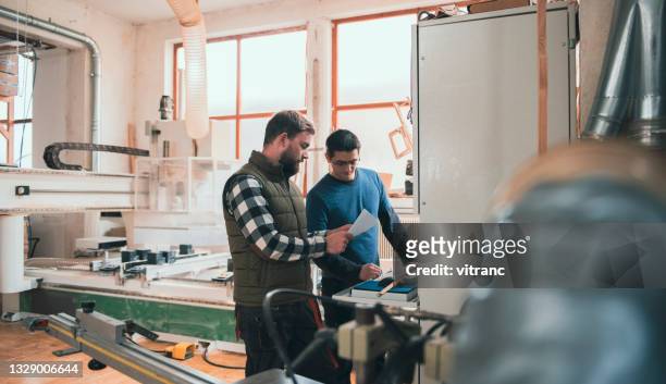 porträt von tischlerarbeitern, die eine cnc-maschine zum schneiden von holzplatten verwenden - cnc machine for wood stock-fotos und bilder