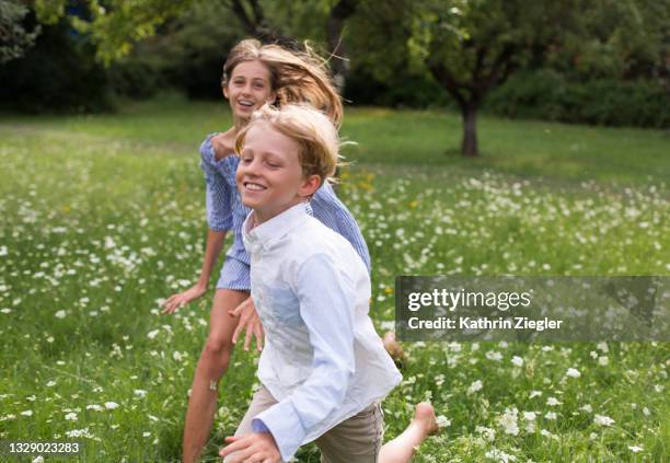 siblings running barefoot in wildflower meadow - weißes kleid stock-fotos und bilder