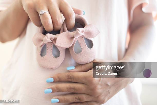 small pink shoes for unborn baby on belly of pregnant woman - baby booties stock pictures, royalty-free photos & images