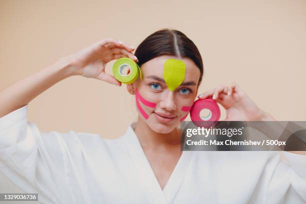 portrait of young woman holding prop while standing against wall - applying plaster stock pictures, royalty-free photos & images