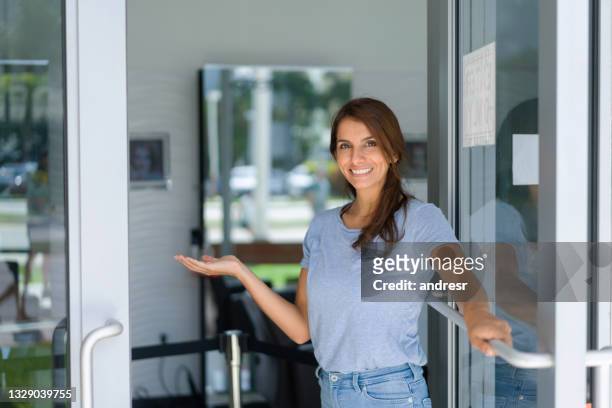 business owner opening the door of her shop and welcoming customers - opening event stock pictures, royalty-free photos & images