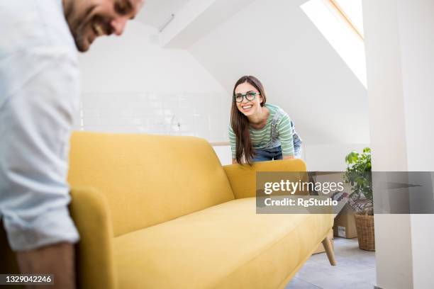 happy couple arranging their new living room - couple couch imagens e fotografias de stock