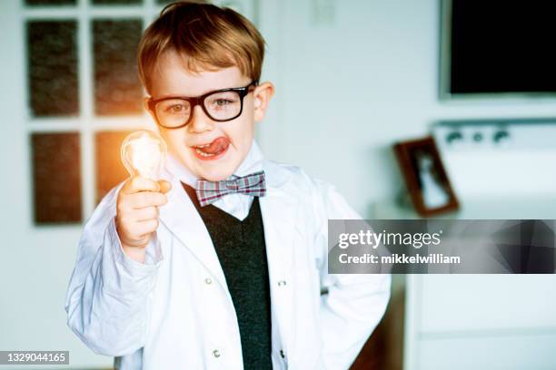 child entrepreneur gets a great idea while holding light bulb - young inventor stock pictures, royalty-free photos & images