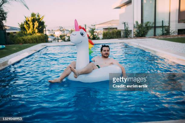 homme sur flotteur de licorne gonflable dans la piscine - float photos et images de collection