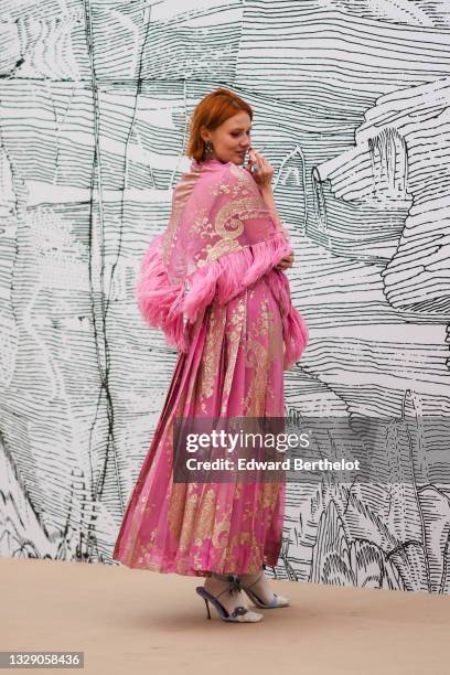 Anna Pahlavi wears silver and black stars pendants earrings, a silver with large cross pendant chain necklace, a silver and blue stone ring, a pink...