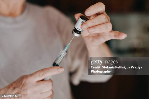 close up on hands filling a syringe with medicine - injecteren stockfoto's en -beelden