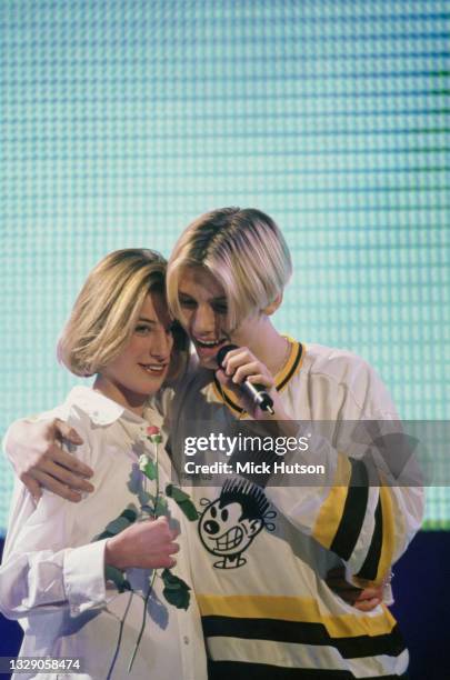 American singer Nick Carter of the Backstreet Boys hugs a fan on stage during a performance, UK, circa 1995.