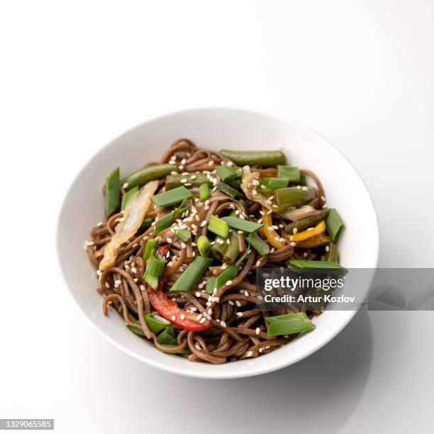 brown spaghetti or pasta with vegetables and sesame seeds. bowl isolated on white background. pan-asian cuisine, spicy food.top view - buckwheat isolated stock pictures, royalty-free photos & images