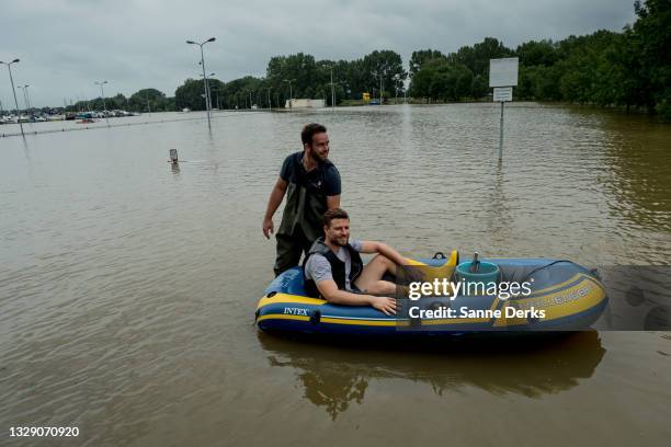 Man pushes another sitting in an inflatable boat on a flooded street on July 16, 2021 in Roermond, Netherlands. The flooding has been caused by...