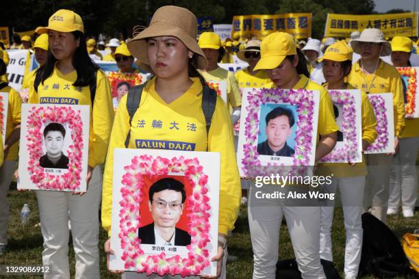 Falun Gong practitioners and supporters hold pictures of victims who were persecuted by the Chinese government as they take part in an annual rally...