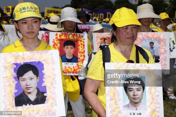 Falun Gong practitioners and supporters hold pictures of victims who were persecuted by the Chinese government as they take part in an annual rally...