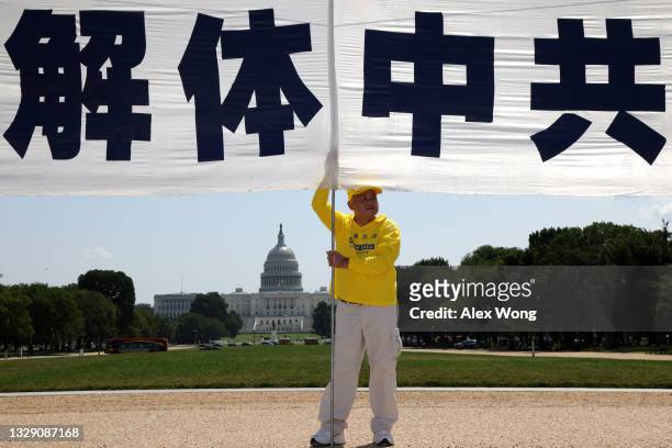 Man holds a banner that reads "Dissolve Chinese Communist Party" during a Falun Gong annual rally and demonstration at the National Mall July 16,...