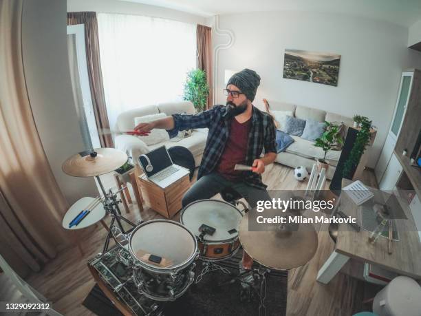 ein junger attraktiver schlagzeuger mit bart spielt in seiner wohnung schlagzeug. - drums stock-fotos und bilder