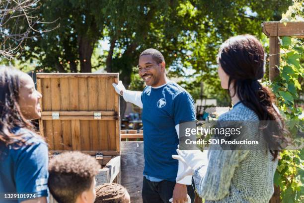 community garden director talks to volunteers about composting - compost bin stock pictures, royalty-free photos & images
