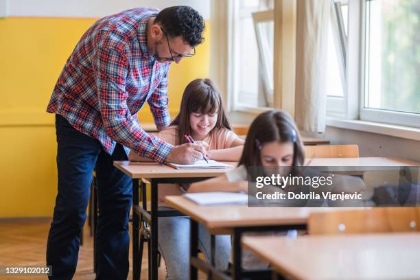 teacher walking from student to student and observing their work - teacher taking attendance stock pictures, royalty-free photos & images