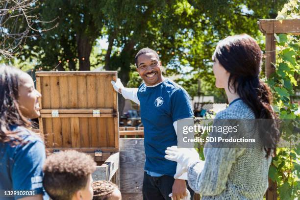 male volunteer holds open lid of composting bin - american influencer stock pictures, royalty-free photos & images