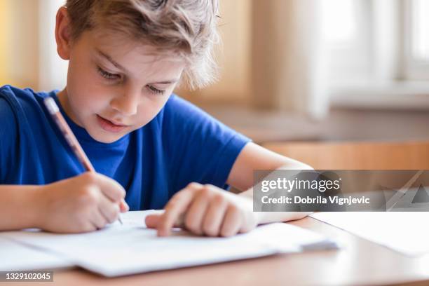 garçon prenant des notes en classe - faire ses devoirs photos et images de collection
