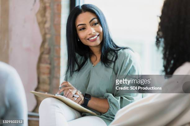 employee engagement coordinator smiles at unrecognizable employee - colleague engagement stock pictures, royalty-free photos & images