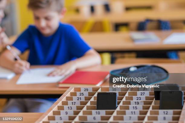 school kids placing putting phones away during class - banned stockfoto's en -beelden