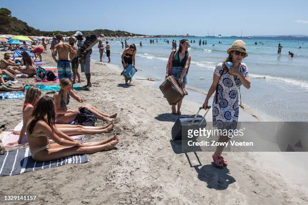 Tourists leave the beach dragging suitcases in the sand on July 16, 2021 in Ibiza, Spain. The Balearic Islands, Spain's holiday archipelagos were...