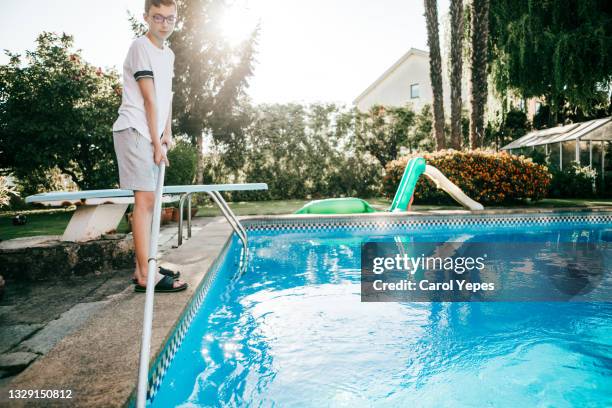 teen boy removing leaves from swimming pool in back yard in summer - swimming pool cleaning stock pictures, royalty-free photos & images