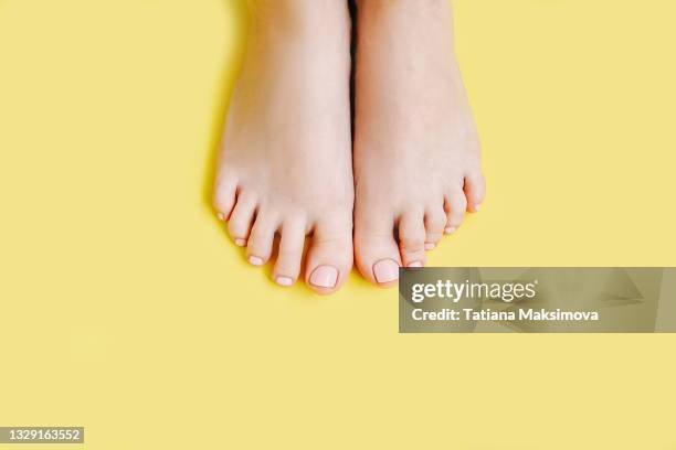 women's toenails with pink pedicure on yellow background. - female feet stockfoto's en -beelden