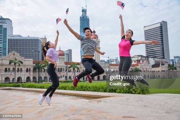 young patriotic malaysians waving malaysian national flags and celebrating the independence day of malaysia on 31st august at merdeka square, kuala lumpur malaysia. - malaysia kuala lumpur merdeka square stock pictures, royalty-free photos & images