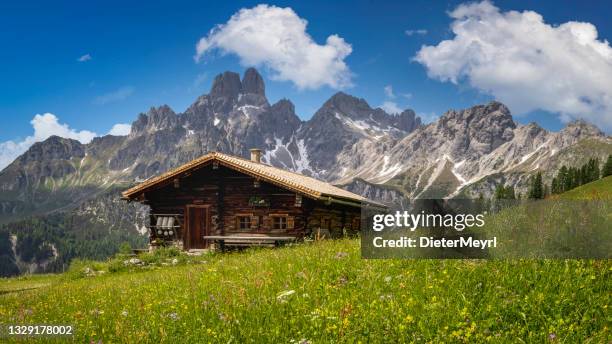 idyllic mountain landscape in the alps: mountain chalet, meadows and blue sky - hut stockfoto's en -beelden