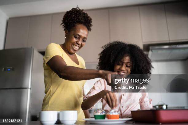 mãe e filha decorando cupcakes juntos em casa - decorating a cake - fotografias e filmes do acervo