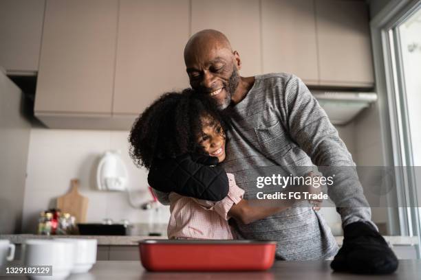 vater und tochter umarmen und kochen gemeinsam zu hause - african american dad stock-fotos und bilder