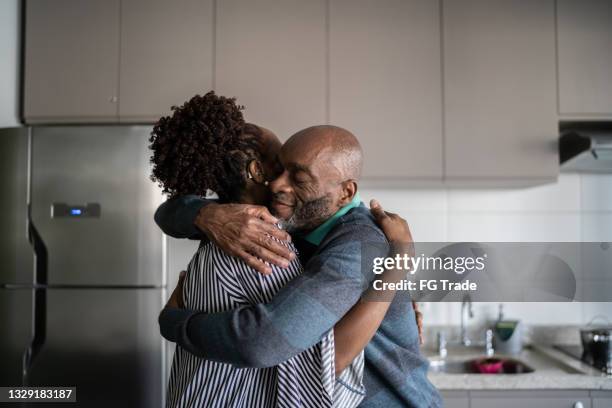 mature couple embracing at home - apologize stockfoto's en -beelden