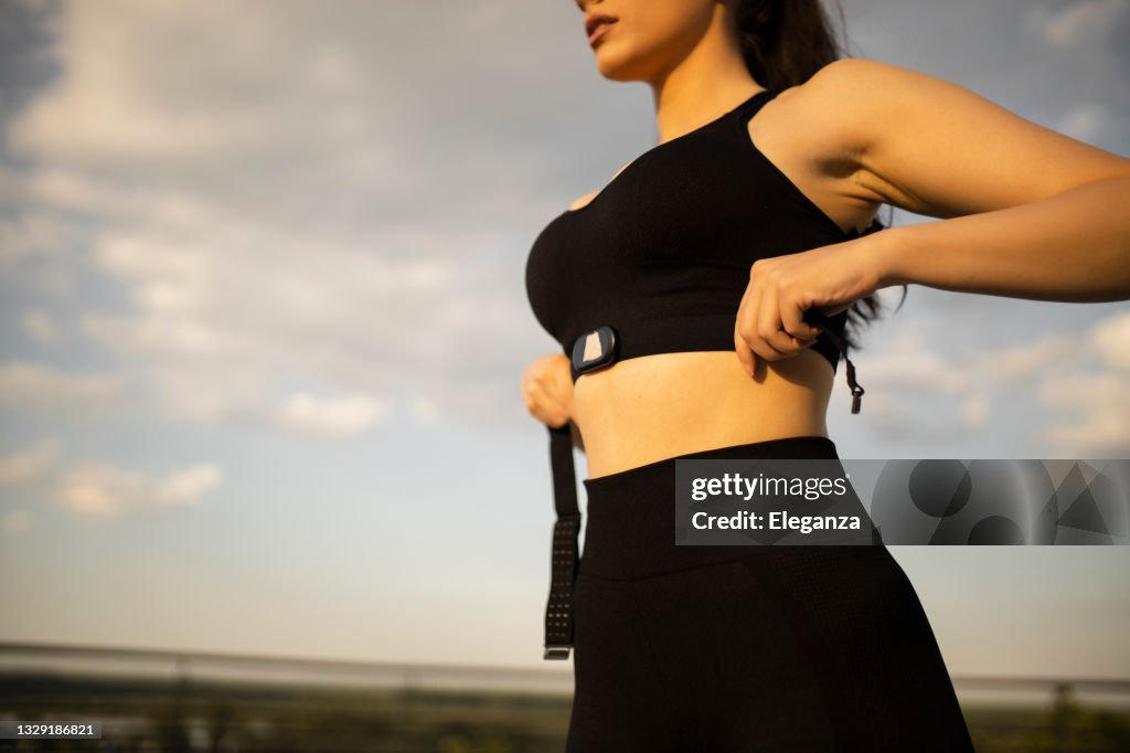 Gros plan sur une femme mettant un tracker de fitness pour surveiller ses calories et sa fréquence cardiaque - concepts d’objectifs de fitness
