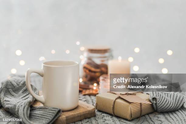 mug of holiday drink, candles, gift box, knitted sweater. hygge concept. cozy mood christmas. - christmas still life - fotografias e filmes do acervo