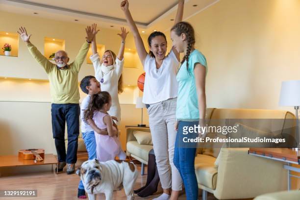a cheering family people is watching a basketball game together on tv. - family tv pet stock pictures, royalty-free photos & images