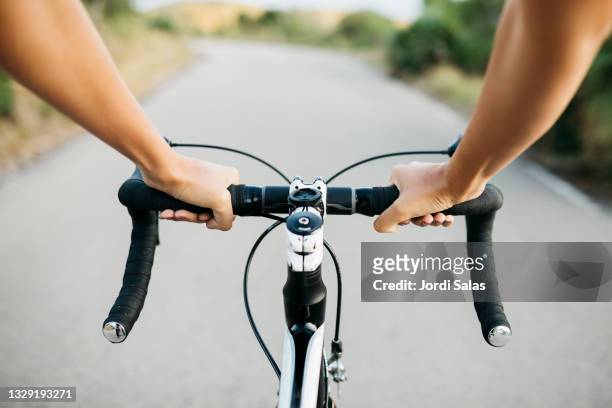 woman's hands on a bicycle's handlebar - handlebar fotografías e imágenes de stock