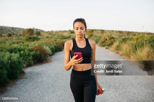 woman texting on an smartphone after workout - aufopferung stock-fotos und bilder