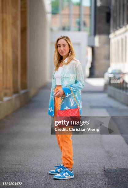 Sonia Lyson is seen wearing Nike sneakers, red Louis Vuitton bag, Louis Vuitton button shirt with logo print, orange pants Zara, white cropped top on...