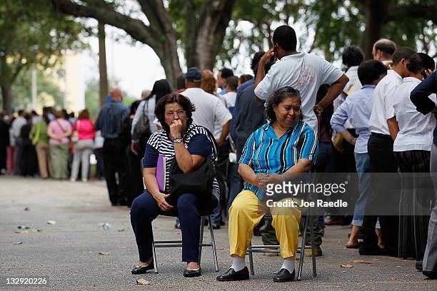Maria and Nikki Picante sit as they wait in line with other job seekers line up to apply for an opening with Major League Baseball's Miami Marlins on...