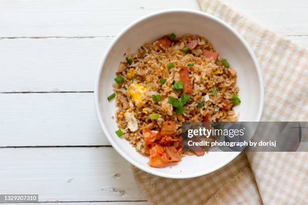 directly above shot of fried rice with kimchi served in white bowl on white wooden table - fried rice stock-fotos und bilder