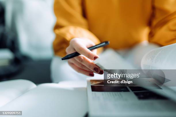 close up, mid-section of focused young asian woman reading book and making notes at home, concentrates on her studies. further education concept - college for creative studies stock pictures, royalty-free photos & images