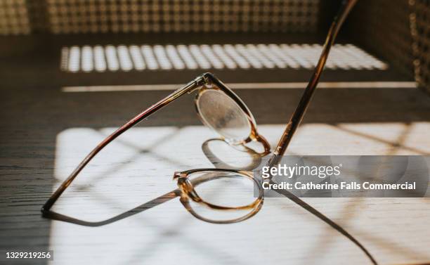 snapped spectacles on a sunny wooden table - brille kaputt stock-fotos und bilder