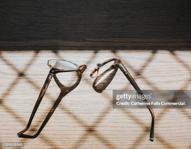 snapped spectacles on a sunny wooden table - kapot stockfoto's en -beelden