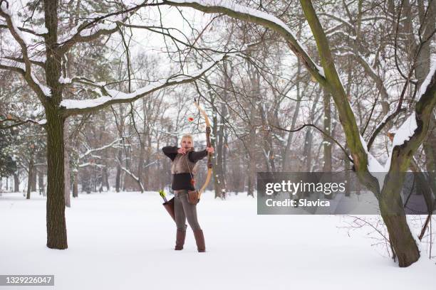 woman hunting with bow and arrow in winter - bow and arrow stock pictures, royalty-free photos & images