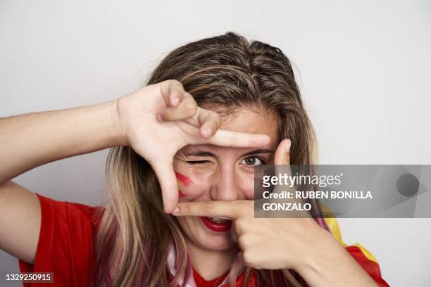 portrait of cheerful teenage girl making frame with fingers and hands while winking an eye. - unterstützer stock-fotos und bilder