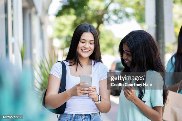 junge frauen lächeln und checken die smartphone-app, während sie gemeinsam in lokalen geschäften einkaufen - smile black white stock-fotos und bilder
