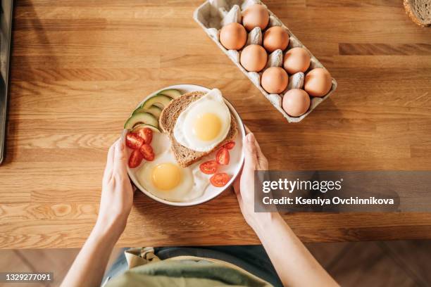 girl hands above frying pan with three cooked eggs, herbs, cheese, tomatoes. woman is making breakfast. top view. copy space - proteina foto e immagini stock