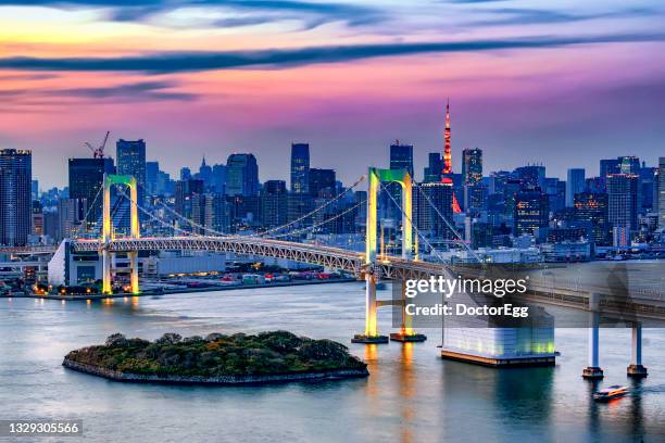 rainbow bridge illumination at sunset with tokyo tower background, odaiba, tokyo, japan - tokyo skyline stock-fotos und bilder